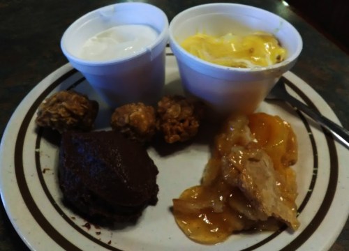 A plate with two cups of dessert, chocolate cake, and fruit cobbler, featuring a mix of sweet treats.