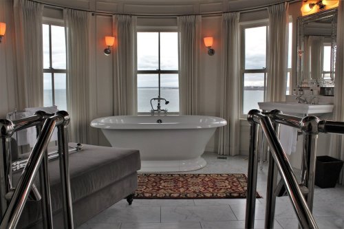 A stylish bathroom featuring a freestanding tub, large windows with a view, and elegant decor.