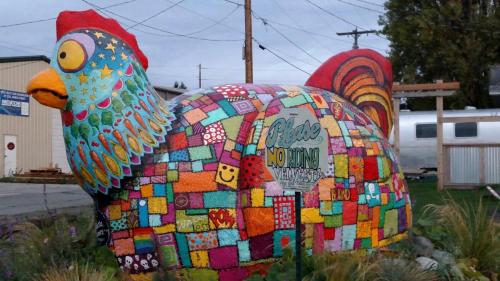 Colorful, large chicken sculpture covered in vibrant patterns and designs, with a sign saying "Please No Hunting."