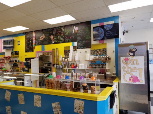 Bright ice cream shop interior with colorful walls, a menu board, and various ice cream flavors displayed.