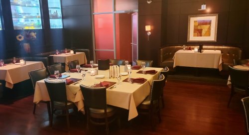 Elegant restaurant interior with tables set for dining, warm lighting, and a cozy atmosphere.