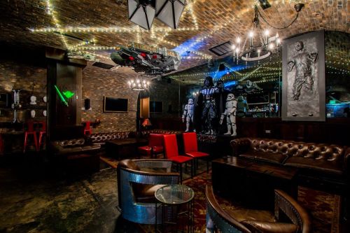 A themed bar with a brick interior, featuring sci-fi decor, including a spaceship and stormtrooper figures.