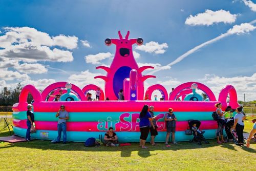 A colorful inflatable octopus slide with people enjoying it on a sunny day.