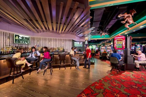 A lively casino bar scene with patrons enjoying drinks, slot machines, and a vibrant atmosphere.