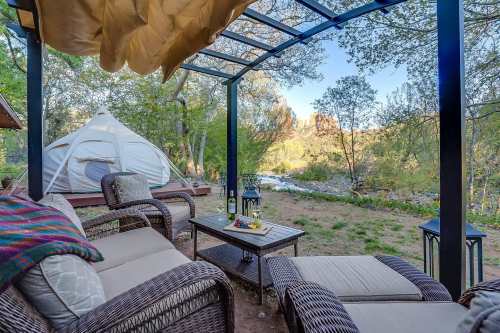 Cozy outdoor seating area with a view of nature, featuring a yurt and a river in the background.