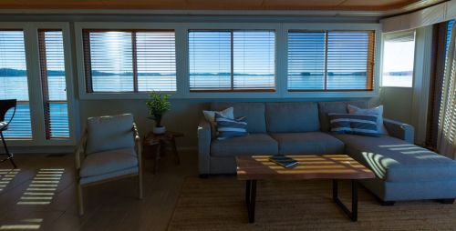A cozy living room with a sofa and coffee table, featuring large windows overlooking a serene lake view.