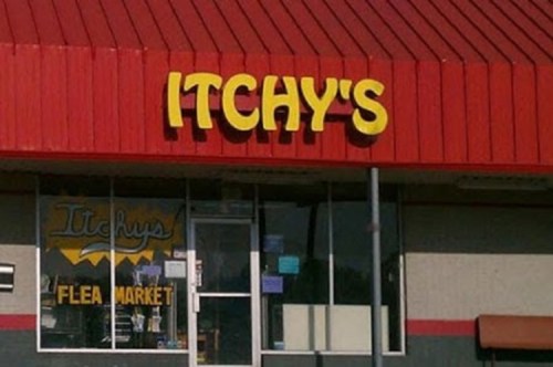A storefront with a red roof and yellow sign reading "ITCHY'S FLEA MARKET." Windows display various items for sale.
