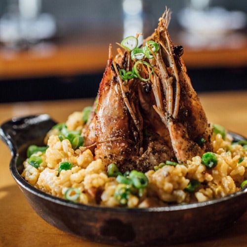 A cast-iron skillet filled with risotto topped with grilled shrimp and green onions.