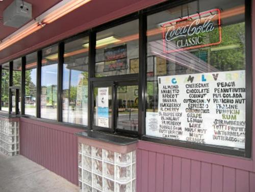 A storefront with a Coca-Cola sign and a menu featuring various ice cream flavors displayed in the window.