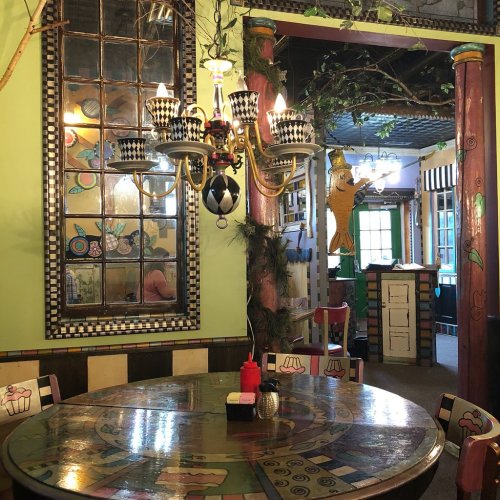 Colorful restaurant interior featuring a round table, unique decor, and a chandelier with playful designs.