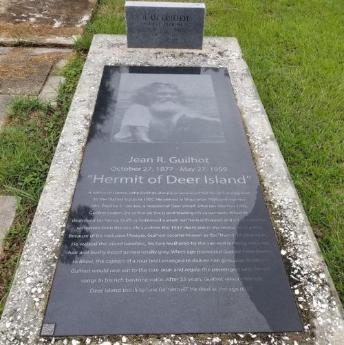 Gravestone of Jean R. Guilhot, "Hermit of Deer Island," detailing his life and legacy from 1877 to 1959.