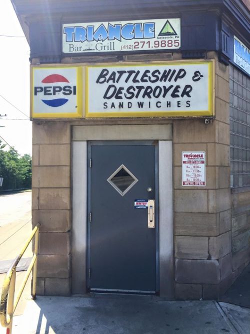 A restaurant entrance with a sign reading "Battleship & Destroyer Sandwiches" and a Pepsi logo above the door.