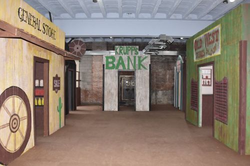 Western-themed interior featuring a bank and general store with wooden facades and rustic decor.