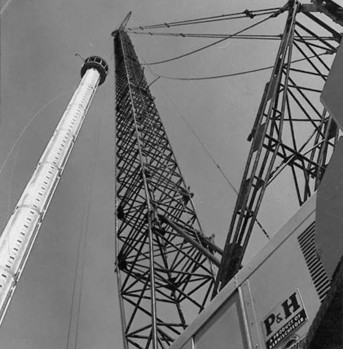 Black and white image of tall industrial cranes against a clear sky, showcasing their structure and machinery.