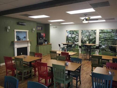 Bright dining area with colorful chairs, wooden tables, and a large mural of trees on the wall. Cozy and inviting atmosphere.
