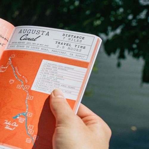 A hand holds an orange map of the Augusta Canal, showing distance, travel time, and points of interest.