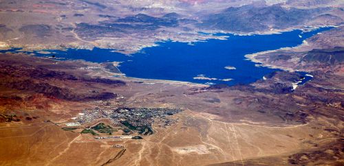 Aerial view of a blue lake surrounded by arid mountains and a small town near the shoreline.