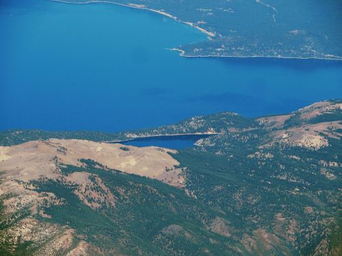 Aerial view of a blue lake surrounded by mountains and a bridge spanning across the water.