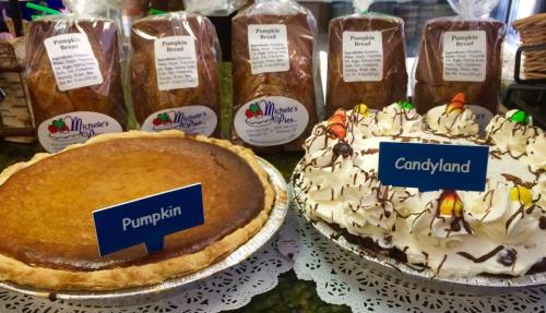 Two desserts: a pumpkin pie and a Candyland cake, with labels. In the background, several loaves of pumpkin bread.