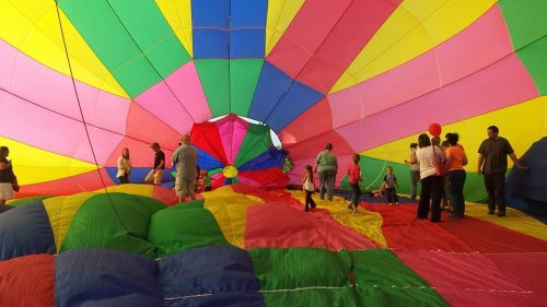 Inside a colorful hot air balloon, people gather on vibrant fabric, enjoying the bright, cheerful atmosphere.