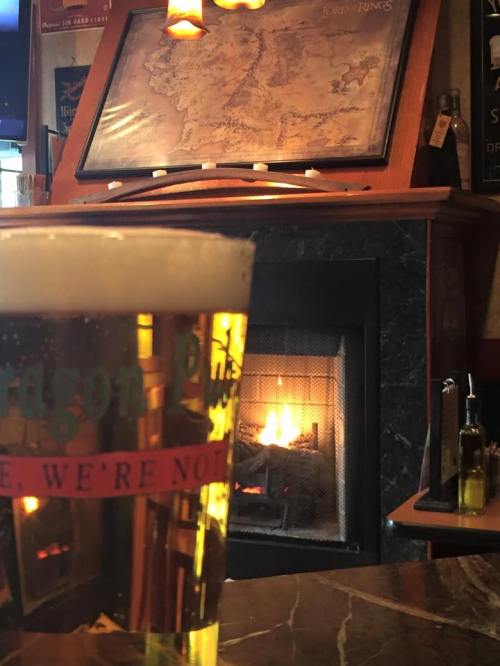 A pint of beer in front of a cozy fireplace, with a map of Middle-earth in the background.