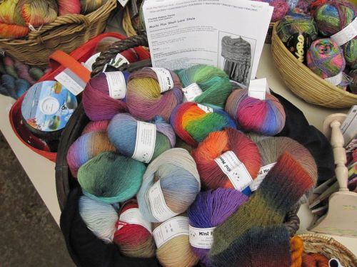 A basket filled with colorful yarn skeins in various shades, alongside a pattern sheet for a shawl.