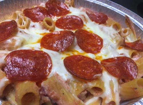 Baked pasta with pepperoni slices and melted cheese in a silver foil dish.