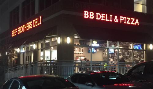 A brightly lit deli and pizza restaurant at night, featuring signs for "Beef Brothers Deli" and "BB Deli & Pizza."
