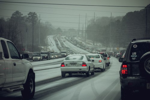 Traffic jam on a snowy road, with vehicles struggling to navigate through winter conditions.