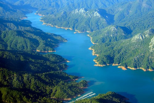 Aerial view of a winding river surrounded by lush green mountains and a serene blue lake.