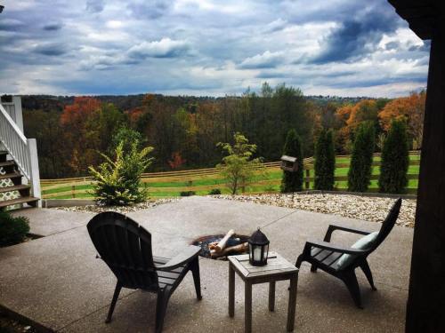 A cozy outdoor seating area with two chairs, a small table, and a fire pit, overlooking a colorful autumn landscape.