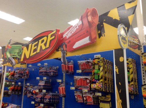 A store display featuring a large Nerf logo and a Mega blaster, with various Nerf products on shelves below.
