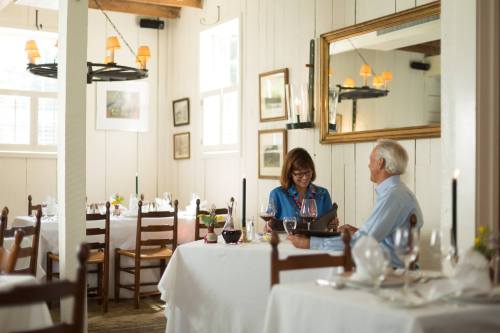 A couple sits at a cozy restaurant table, enjoying wine and looking at a menu in a warmly lit setting.