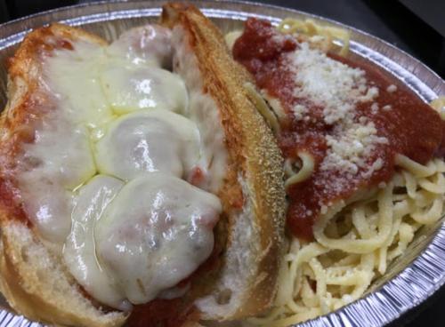 A close-up of a dish featuring a cheesy meatball sub alongside a serving of spaghetti with marinara sauce.