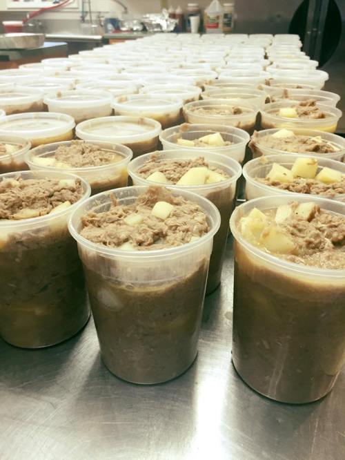 Containers filled with a meat and potato dish, lined up on a kitchen counter.