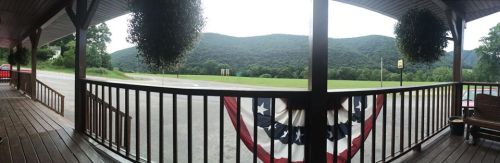 A panoramic view from a porch, featuring mountains in the background and decorative bunting in the foreground.