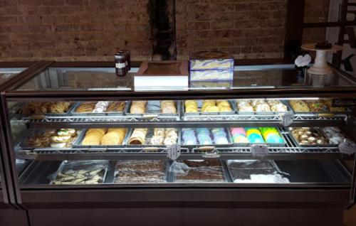 A display case filled with a variety of colorful baked goods, including cookies, pastries, and desserts.