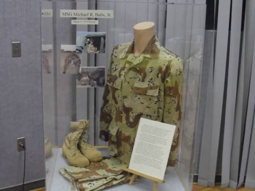 Display case featuring military uniform, boots, and a plaque honoring MSG Michael R. Balis, Jr.