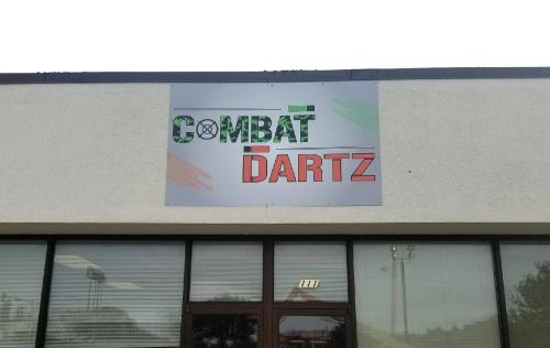 Sign for "COMBAT DARTZ" displayed on a building exterior, featuring bold, colorful lettering.