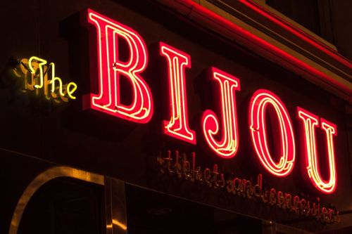 Neon sign for "The BIJOU" with a vintage style, glowing against a dark background.