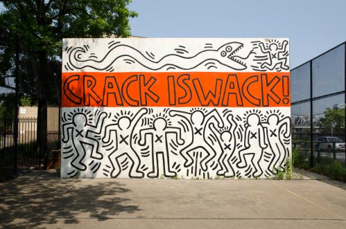 A vibrant mural featuring the text "CRACK IS WACK!" with dancing figures and a snake design on a white wall.