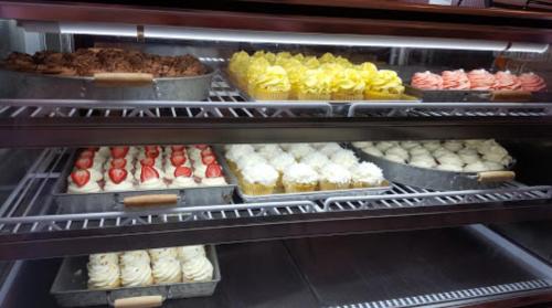 A display case filled with various colorful cupcakes, including chocolate, yellow, pink, and white frosted options.