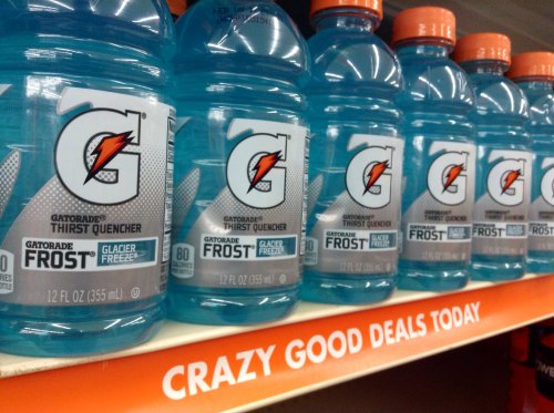 A row of Gatorade Frost Glacier Freeze bottles on a store shelf, with a sign reading "Crazy Good Deals Today."