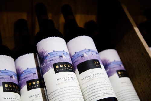 Bottles of Merlot Reserve wine lined up on a shelf, featuring elegant labels with a vineyard image.