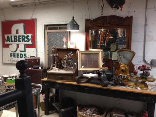 A vintage shop display featuring antique items, including scales, mirrors, and decorative objects on a wooden table.