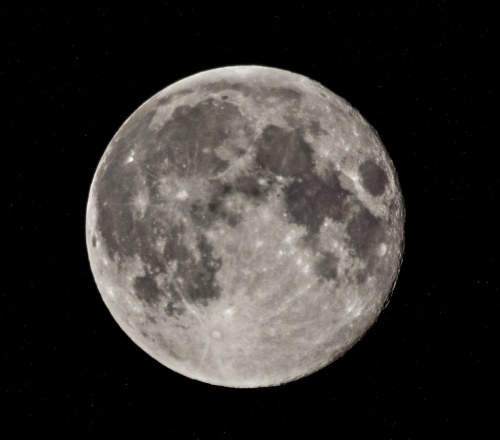 A close-up view of the full moon against a black sky, showcasing its craters and surface details.