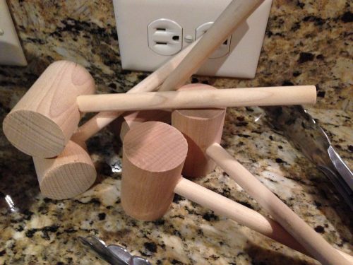 A pile of wooden mallets and a stick resting on a granite countertop near electrical outlets.