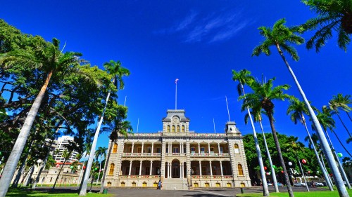 Historic building with ornate architecture, surrounded by palm trees and a clear blue sky.
