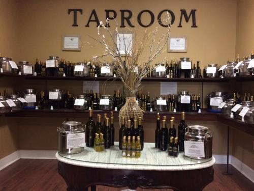 A cozy taproom with shelves of bottles, a decorative vase, and a marble table in the center.