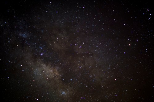 A starry night sky filled with countless stars and a faint Milky Way galaxy visible in the background.